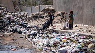 أطفال نازحون يفرزون القمامة في أحد شوارع دير البلح وسط قطاع غزة، الثلاثاء، 27 أغسطس/آب 2024