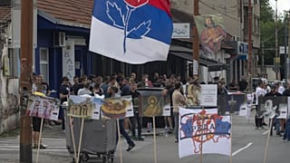 Bir kişi, Kosova'nın Mitrovica kentindeki köprüdeki barikatın bir parçası olan yanmış bir kamyonun fotoğraflarını çekiyor, 29 Aralık 2022.