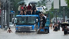 Des personnes sont montées sur un camion pour éviter les inondations causées par les fortes pluies de la tempête tropicale Yagi, appelée localement Enteng, lundi 2 septembre