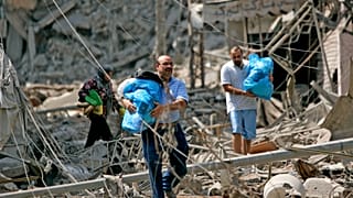 لبنانيون من سكان الضاحية الجنوبية لبيروت يجمعون أمتعتهم أثناء فرارهم من منازلهم المدمرة في لبنان في 23 يوليو/تموز 2006. 