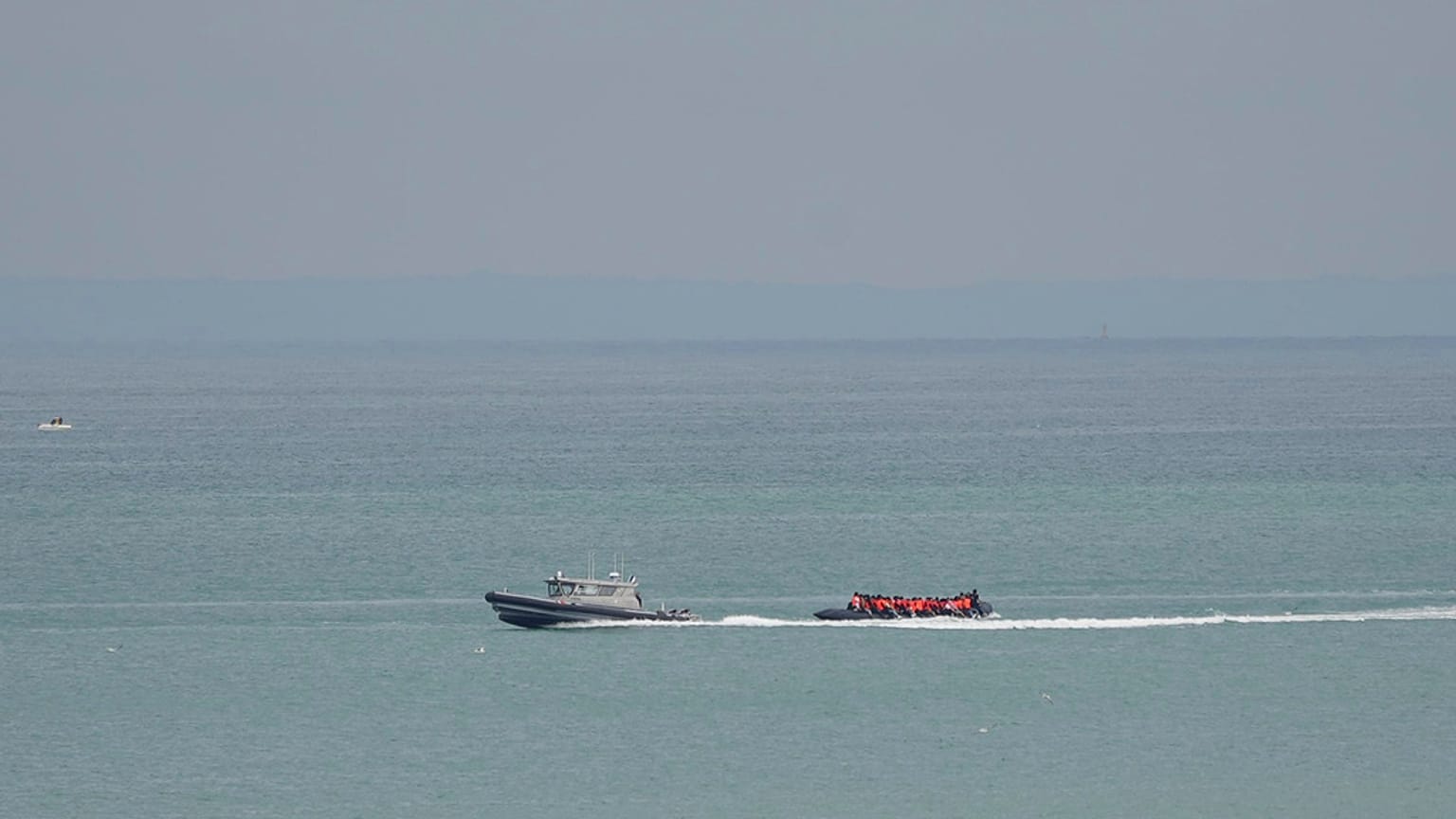 A boat thought to be with migrants is escorted by a vessel from the French Gendarmerie Nationale off the Wimereux beach, France