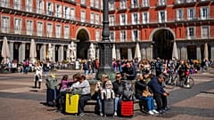 Touristen sitzen auf einer öffentlichen Bank auf der Plaza Mayor im Zentrum von Madrid, Spanien, Montag, 29. April 2024.