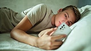 Un joven visualiza su teléfono móvil.