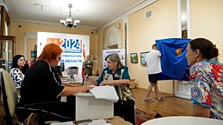 A woman receives her ballot at a polling station during the three-day Kursk region governor election, in Kursk, Russia, Sunday, Sept. 8, 2024. 