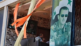 صورة الرئيس السوري بشار الأسد على واجهة محل تعرض للدمار من الغارات الإسرائيلية على حماة