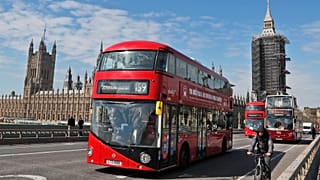 Otobüsler Londra'da, Parlamento Binası ve Elizabeth Kulesi'nin arka planında yer alan Westminster Köprüsü'nden geçiyor, 27 Nisan 2021