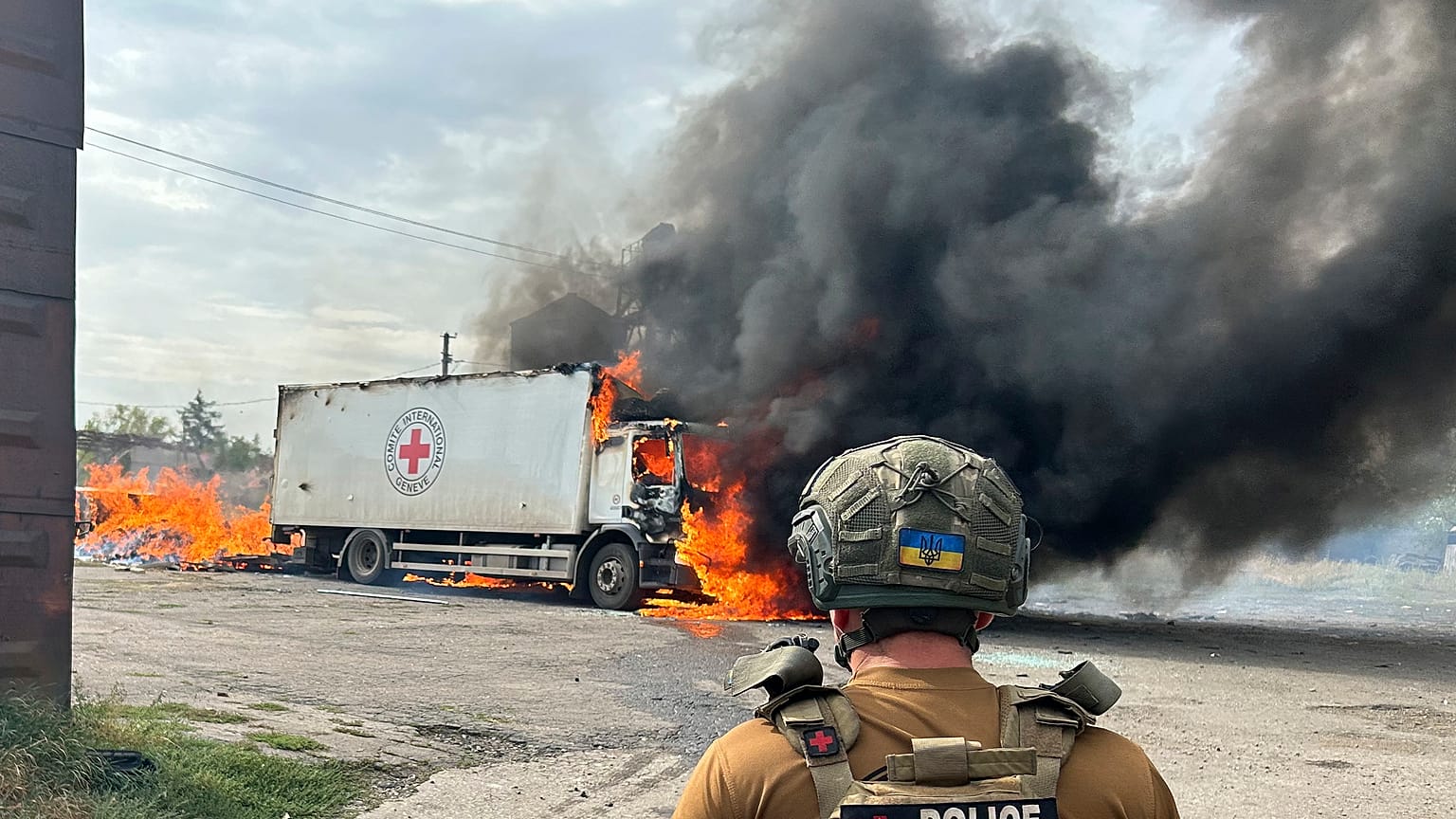 A police officer looks at a burning Red Cross vehicle that was destroyed in a Russian strike in Donetsk, September 12, 2024