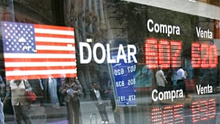 أشخاص ينظرون إلى نافذة وهم ينظرون إلى لافتة تظهر سعر صرف الدولار الأمريكي مقابل البيزو التشيلي في مكتب صرافة في سانتياغو، الخميس 9 أكتوبر/تشرين الأول 2008. 