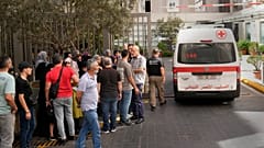 Una ambulancia de la Cruz Roja Libanesa pasa junto a los familiares de las víctimas heridas por la explosión de sus localizadores portátiles.