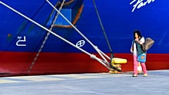 A passenger walks past a docked ship during a 48-hour strike in the port of Piraeus, near Athens, Greece, 