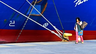 A passenger walks past a docked ship during a 48-hour strike in the port of Piraeus, near Athens, Greece, 