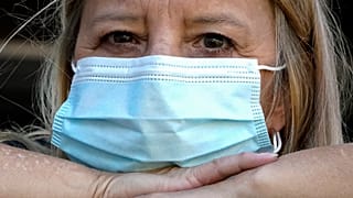 FILE - A woman wears a mask at her home after previously having COVID.