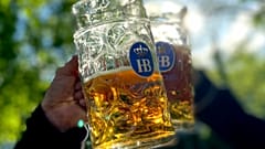 Im Taxisgarten in München stoßen die Menschen mit ihren Bierkrügen an.