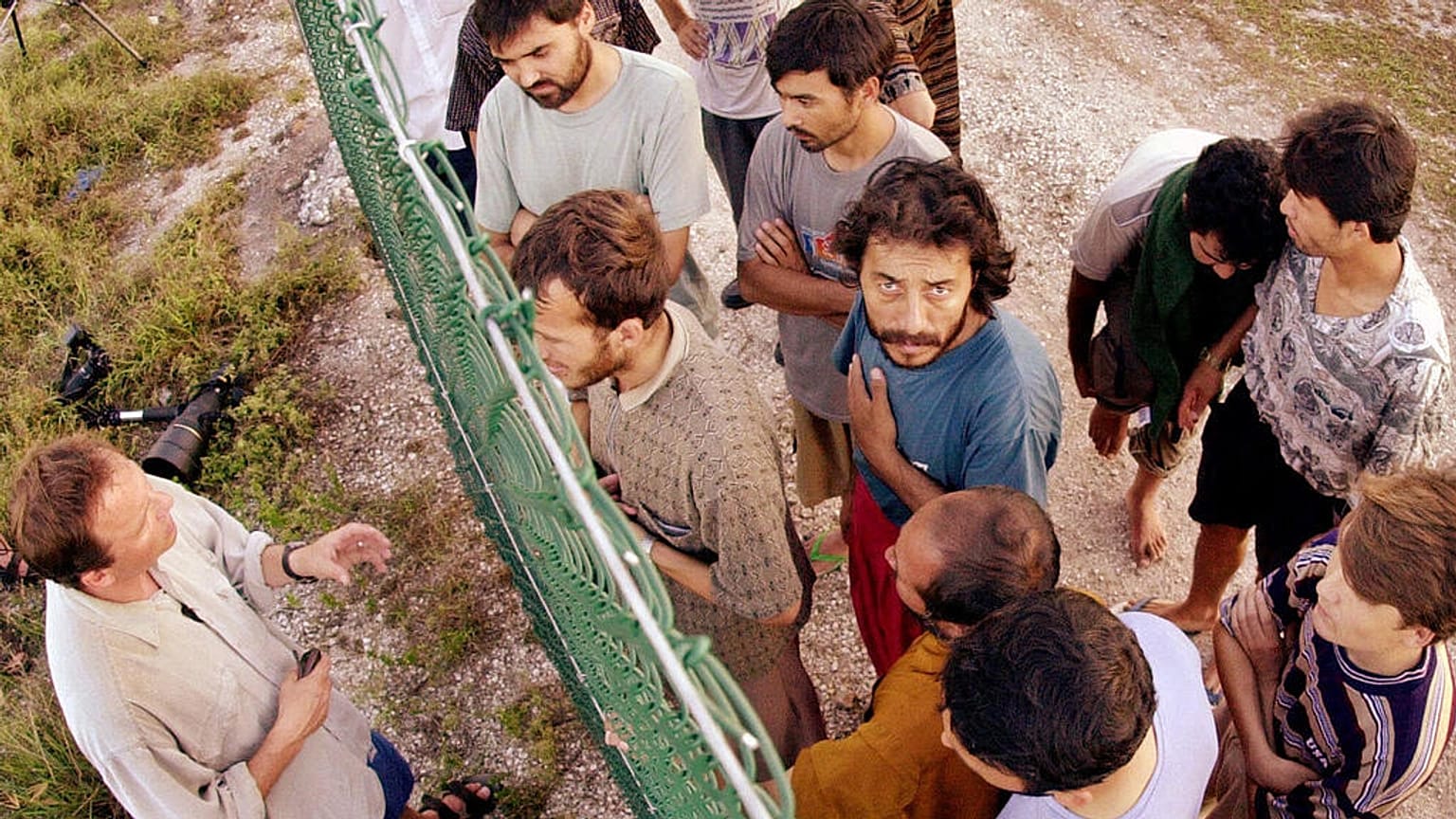 DOSYA - Mülteciler, kendilerini Nauru Adası'na getiren yolculukları hakkında uluslararası gazetecilerle konuşmak için bir çitin bir tarafında toplanıyor, 19 Eylül 2001. 