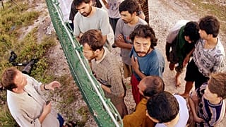 DOSYA - Mülteciler, kendilerini Nauru Adası'na getiren yolculukları hakkında uluslararası gazetecilerle konuşmak için bir çitin bir tarafında toplanıyor, 19 Eylül 2001. 