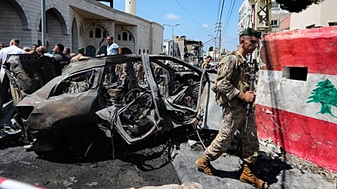 A Lebanese army soldier passes in front a car that was hit by an Israeli strike in the southern port city of Sidon, Lebanon, Wednesday, Aug. 21, 2024. (AP Photo/Mohammad Zaata