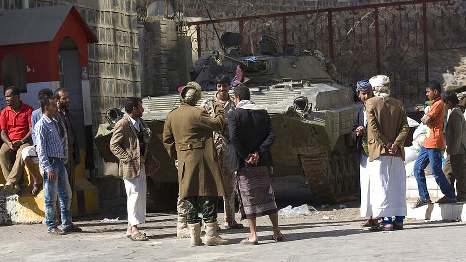 أشخاص ويمنيون حوثيون شيعة يرتدون زي الجيش يقفون بالقرب من عربة مدرعة تم الاستيلاء عليها من الجيش خلال الاشتباكات الأخيرة أمام منزل الرئيس اليمني عبد ربه منصور هادي في صنعاء، ا