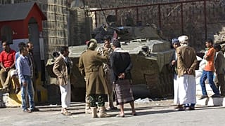 أشخاص ويمنيون حوثيون شيعة يرتدون زي الجيش يقفون بالقرب من عربة مدرعة تم الاستيلاء عليها من الجيش خلال الاشتباكات الأخيرة أمام منزل الرئيس اليمني عبد ربه منصور هادي في صنعاء، ا