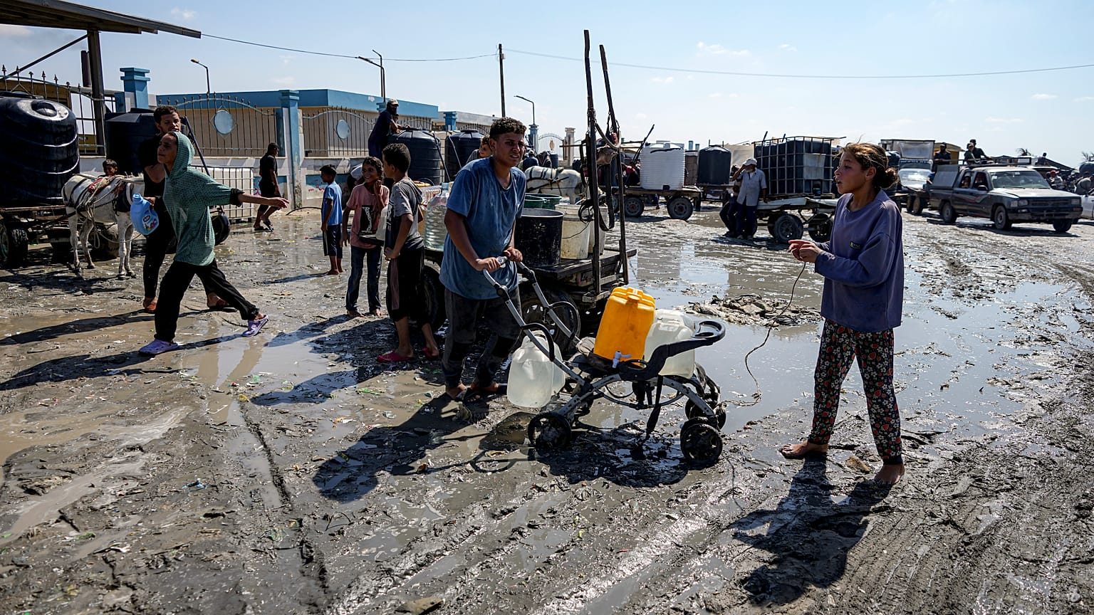 فلسطينيون يتجمعون لملء أباريق المياه في مخيم مؤقت في دير البلح وسط قطاع غزة، الخميس، 29 أغسطس/آب 2024