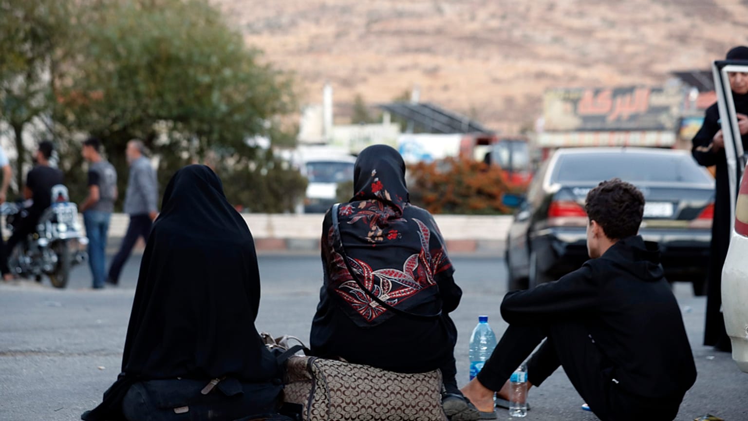 لبنانيون نزحوا جراء القصف الإسرائيلي، يجلسون على الأرض بعد عبورهم إلى سوريا عند المعبر الحدودي السوري اللبناني، سوريا، الثلاثاء، 24 سبتمبر، 2024.