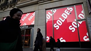 La gente pasa por delante de una tienda que muestra pancartas anunciando 'Rebajas' durante el primer día de las rebajas de invierno en París, el miércoles 10 de enero de 2024.