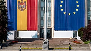 Une femme passe devant le bâtiment du gouvernement, décoré des drapeaux de l'Union européenne et de la Moldavie, à Chisinau, en Moldavie, le 31 mai 2023.