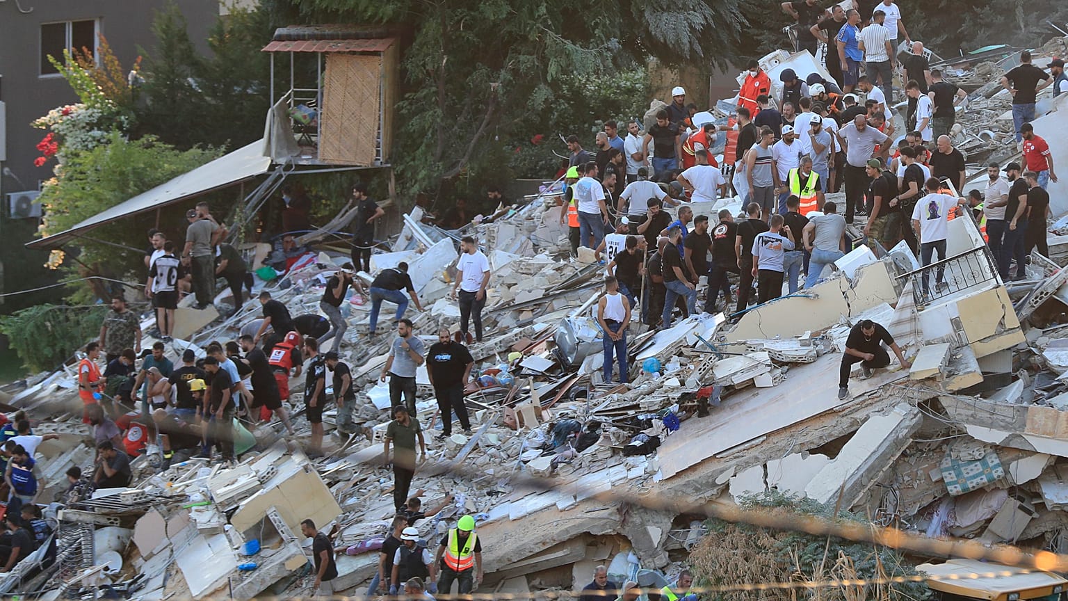 Civili e soccorritori cercano le vittime dopo un attacco aereo israeliano che ha colpito due edifici adiacenti nella città portuale meridionale di Sidone