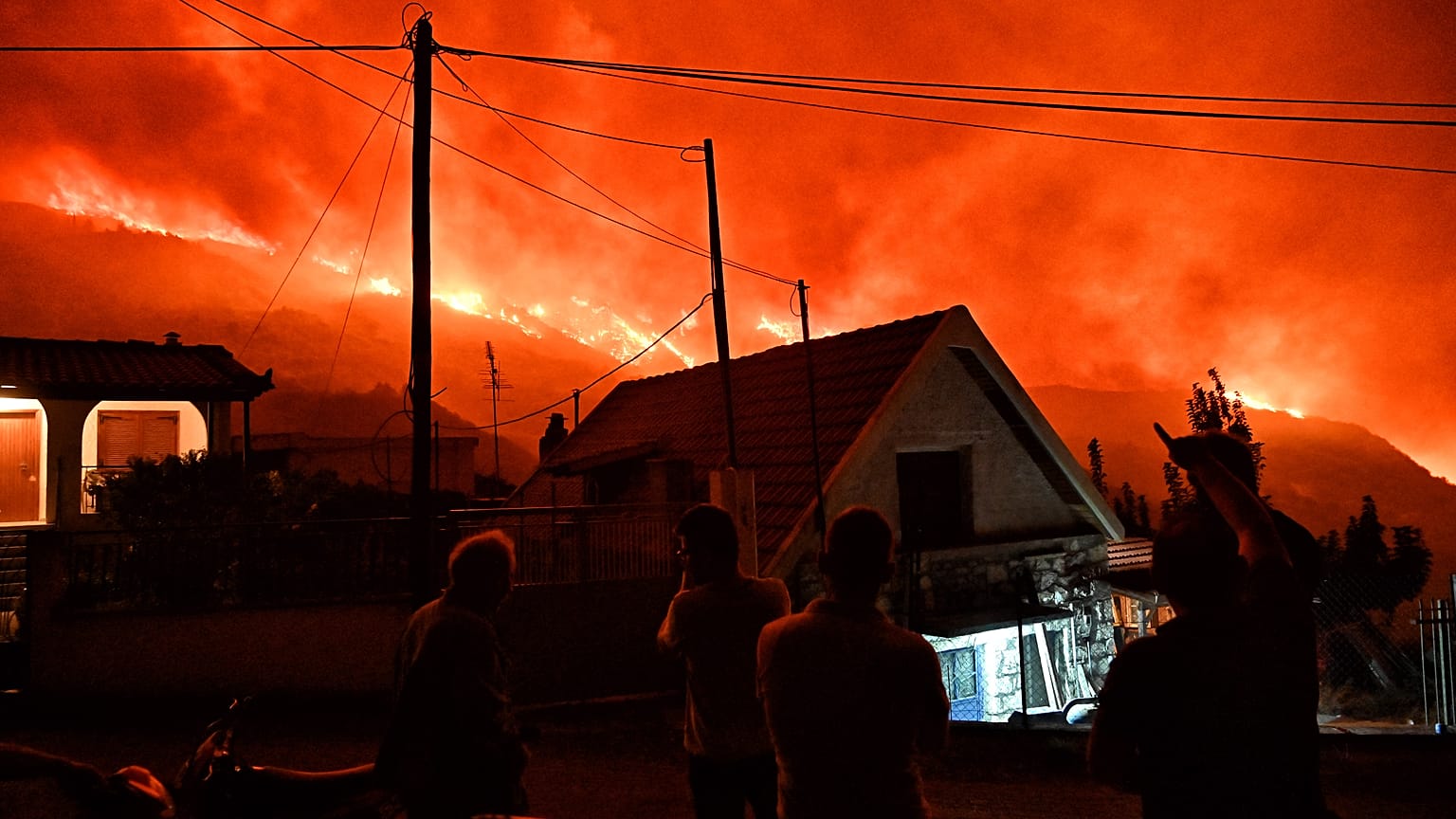Κάτοικοι κοιτούν πυρκαγιά που μαίνεται στην περιοχή Καλλιθέα, στο Ξυλόκαστρο Κορινθίας,