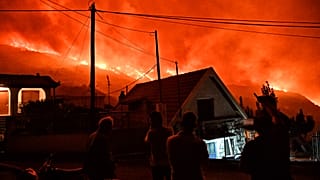 Κάτοικοι κοιτούν πυρκαγιά που μαίνεται στην περιοχή Καλλιθέα, στο Ξυλόκαστρο Κορινθίας,
