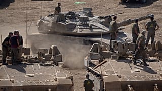 An Israeli tank moves next to soldiers as they stand atop of armoured personnel carriers (APC), in northern Israel, 30 September 2024