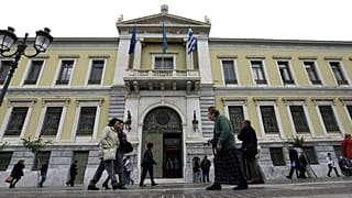 Pedestrians pass outside the headquarters of the National Bank of Greece in Athens. 30 October, 2015.
