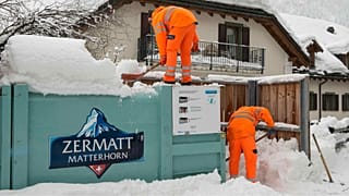Trabalhadores comunitários removem a neve em torno de uma lixeira em Zermatt, Suíça, terça-feira, 9 de janeiro de 2018.