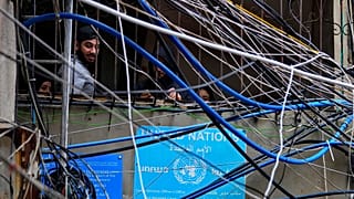 Filistinliler, Beyrut'un güneyindeki Bourj al-Barajneh Filistin mülteci kampında elektrik kabloları ve su borularının arasından bakıyor, 5 Şubat 2024.