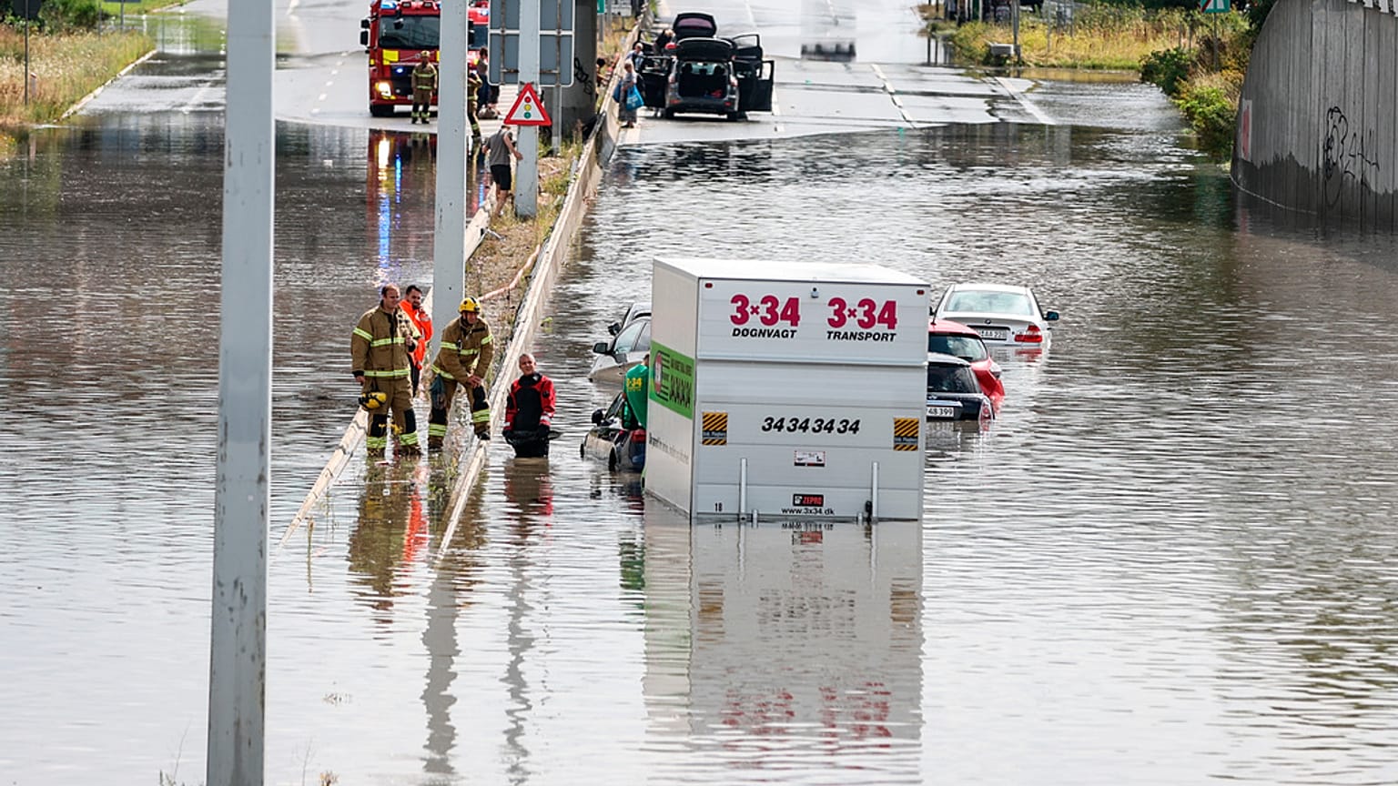 Firefighters work at a flooded road in Copenhagen, Sunday, Aug. 4, 2024. 