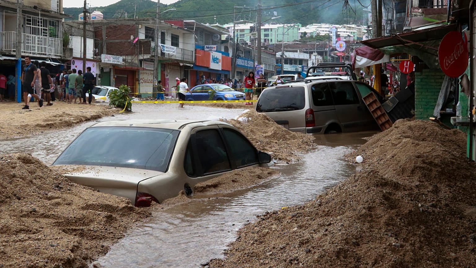 Veículos parcialmente submersos numa rua inundada após a passagem do furacão John em Acapulco, México, no sábado, 28 de setembro de 2024