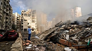 Bir adam, Beyrut'un güney banliyösünde İsrail hava saldırısı alanındaki hasarlı binaları belgeliyor, 1 Ekim 2024.