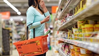 Uma mulher com um cesto de compras num supermercado