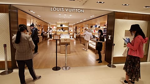 Customers wait in front of a luxury shop in Milan, Italy, Monday, May 18, 2020. Italy is slowly lifting sanitary restrictions after a two-month coronavirus lockdown. 