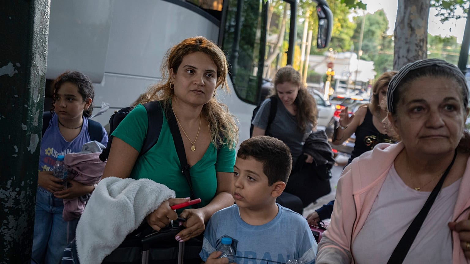 Des citoyens grecs, qui ont été évacués du Liban à bord d'un avion de transport militaire grec, se tiennent devant le bâtiment du ministère grec des Affaires étrangères à Athènes, le 3 octobre 2024.