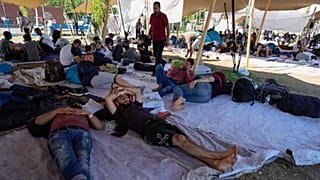 Os migrantes procuram abrigo no exterior de um centro de requerentes de asilo sobrelotado em Ter Apel, no norte dos Países Baixos, na quinta-feira, 25 de agosto de 2022.