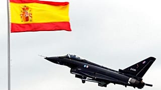 Un Eurofighter vuela cerca de una bandera de España durante un ensayo