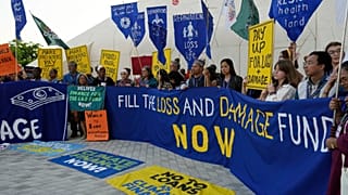 Activistas manifestam-se com um cartaz que diz "encher o fundo de perdas e danos agora" na COP28, no ano passado.