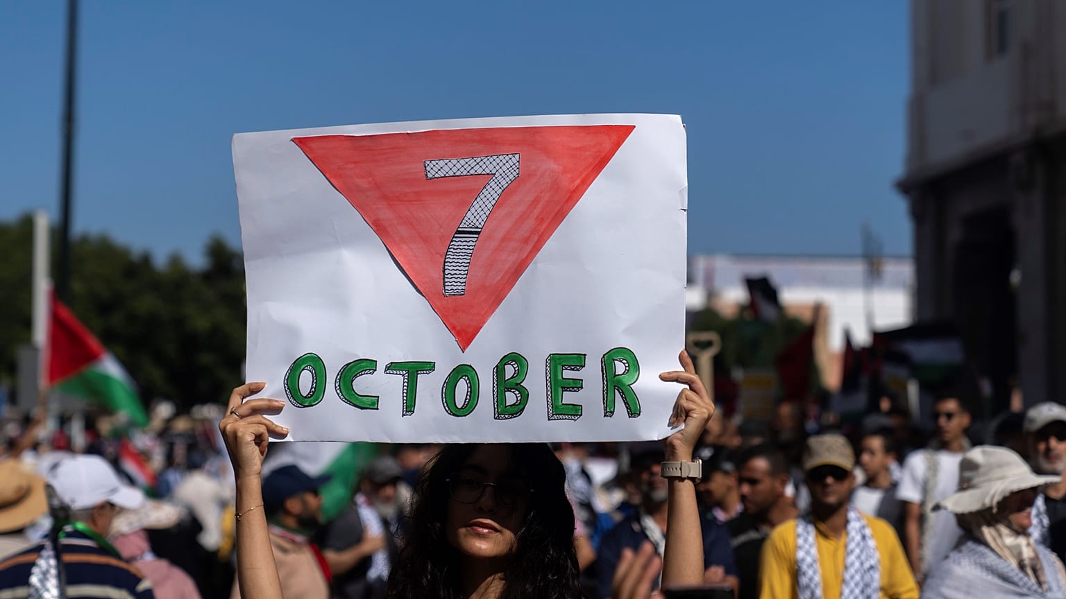 شابة مغربية تحمل لافتة كتب عليها 7 أكتوبر مع السهم الأحمر الخاص بكتائب القسام في غزة خلال مسيرة تضامنية مع غزة ولبنان بالعاصمة الرباط 06/10/2024