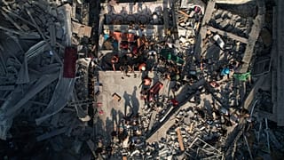  فلسطينيون يتفقدون أنقاض المباني التي استهدفتها غارة جوية إسرائيلية في مخيم الشاطئ للاجئين