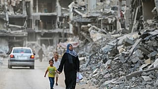 Una familia camina entre los escombros tras una ofensiva israelí en Jebaliya, en el norte de la Franja de Gaza