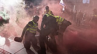 Ein pro-palästinensischer Demonstrant mit einer Rauchbombe wird von der Polizei in Amsterdam, Niederlande, am Montag, 7. Oktober 2024, festgenommen.