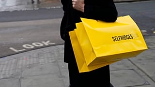 Bir kadın Londra'daki bir mağazadan aldığı alışveriş çantasını taşıyor
