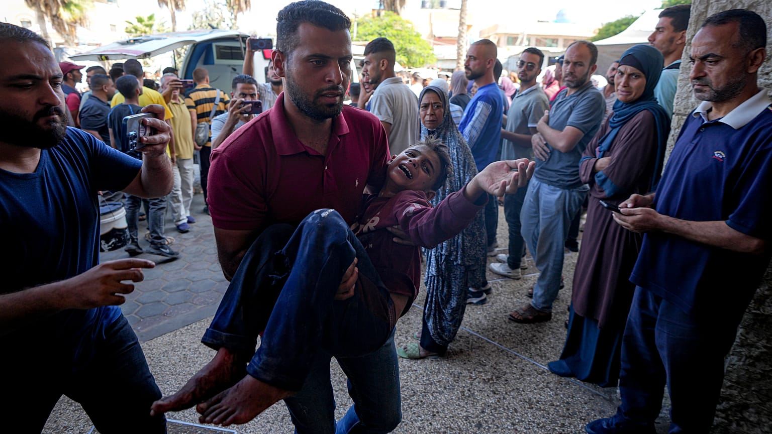 فلسطيني يحمل طفلًا مصابًا بعد غارة جوية إسرائيلية في دير البلح، قطاع غزة، الخميس، 10 أكتوبر/تشرين الأول 2024.