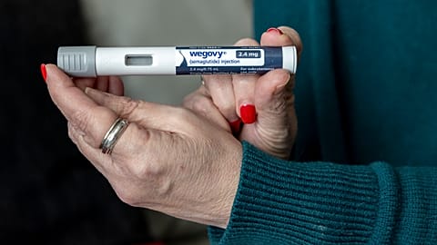 A woman holds up a dosage of Wegovy, a drug used for weight loss.