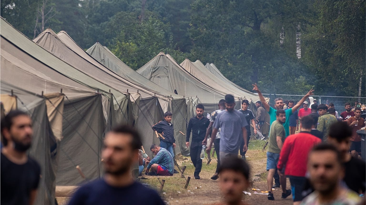مهاجرون يسيرون داخل مخيم اللاجئين الذي تم بناؤه حديثًا في ساحة التدريب العسكرية في رودينكاي، على بعد حوالي 38 كيلومترًا (23.6 ميلًا) جنوب فيلنيوس، ليتوانيا، الأربعاء 4 أغسطس 